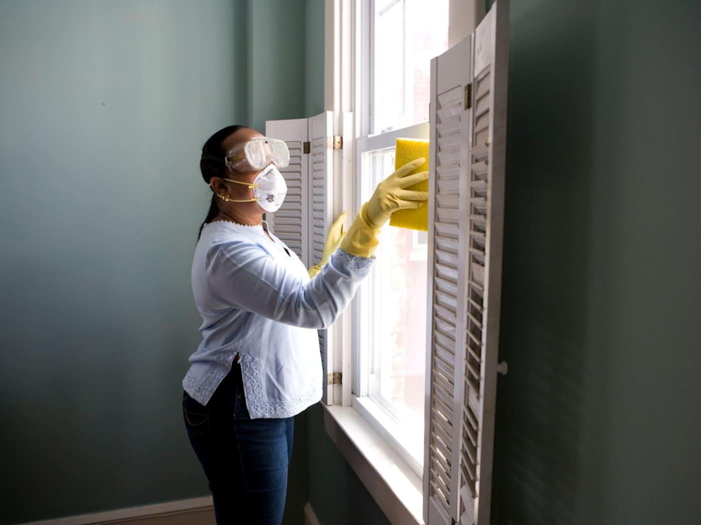 Professional cleaner detailing windows with protective gear